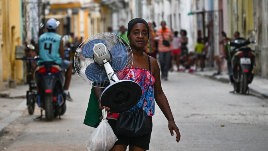 A woman carries a fan along a street in Havana during a nationwide power cut. AFP/Yamil Lage