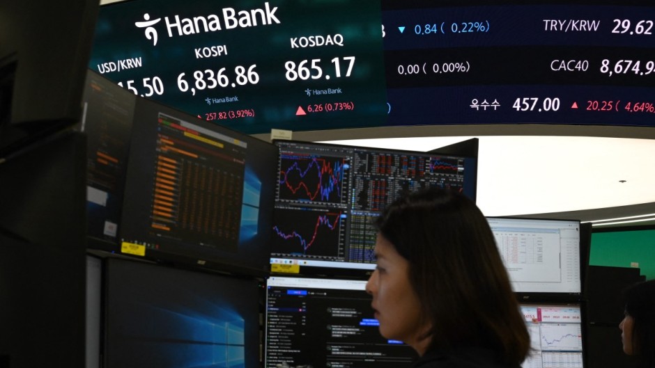 A dealer works near a screen showing South Korea’s benchmark KOSPI stocks index. AFP/Greg Baker
