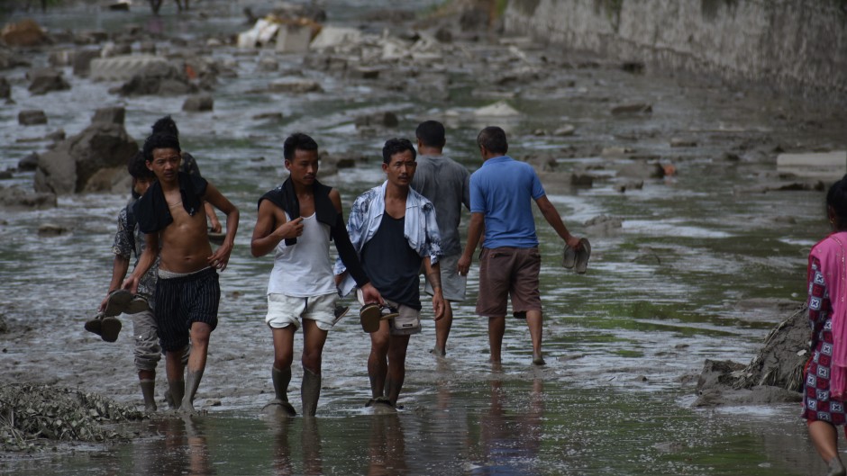 People walk along a road covered by floodwaters in Nuwakot, Nepal, on 26 August. Sunil Pradhan/Anadolu via Getty Images