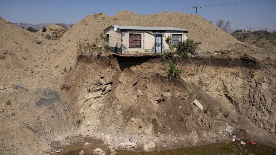 A house overlooks an open pit dug by illegal miners searching for chrome in Bapong