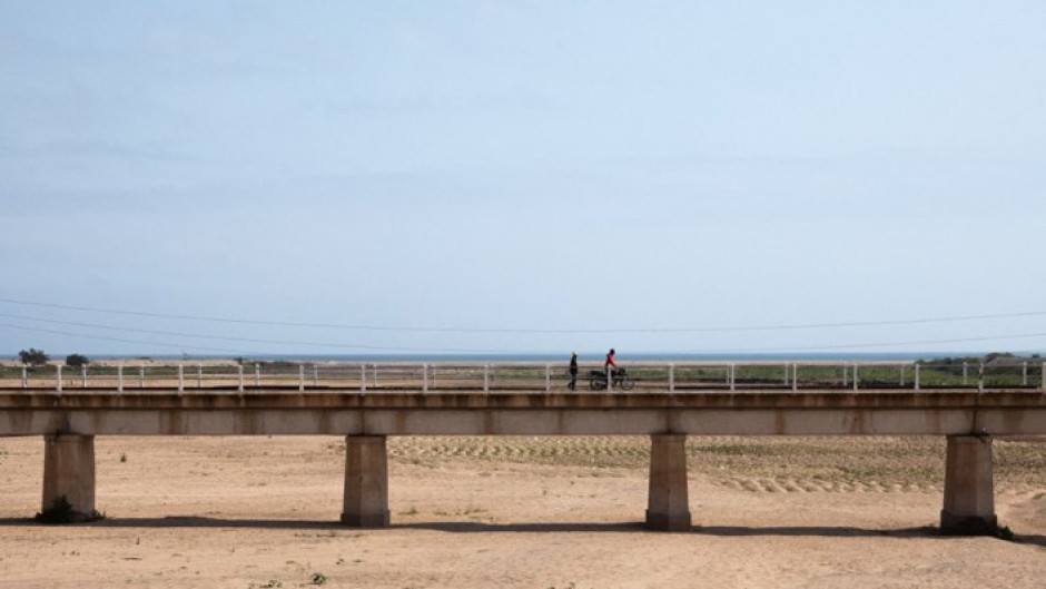 Men crossing a bridge over a dry river in Namibe Province, Angola. Eric Lafforgue/Hans Lucas via AFP