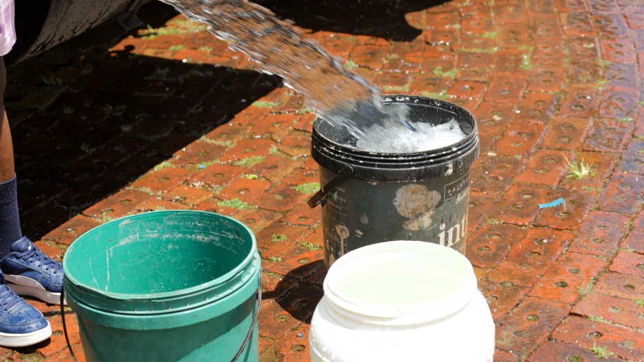 Buckets being filled with water from a water tanker.