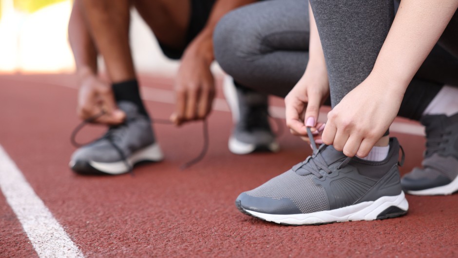File:  Runners tying shoelaces of their sneakers. GettyImages/Olga Yastremska
