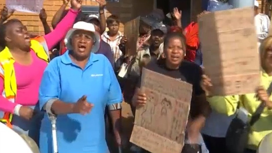 The Kempton Park community and local runners are gathered outside the Kempton Park Police Station.