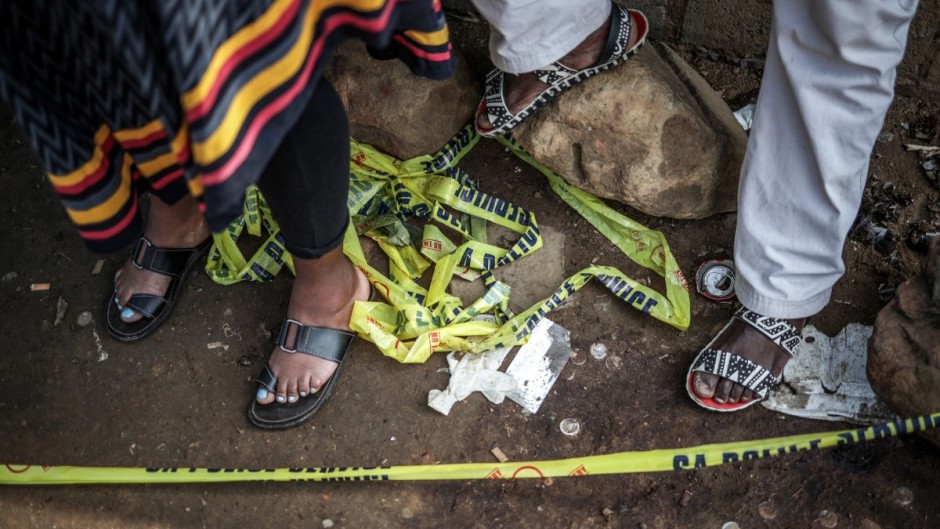 File: Residents stand behind police tape near a crime scene. AFP/Emmanuel Croset