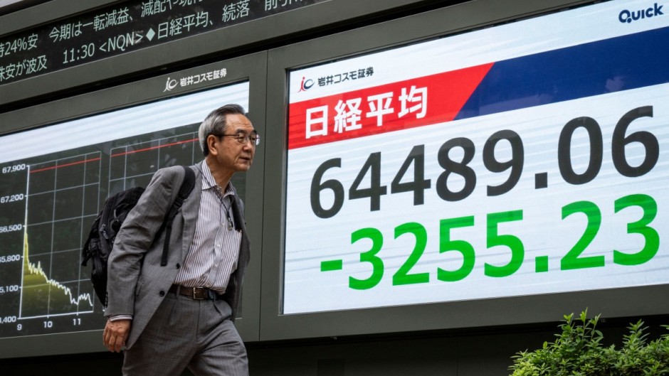 A man walks past an electronic quotation board displaying the Nikkei Stock Average on the Tokyo Stock Exchange. AFP/Yuichi Yamazaki