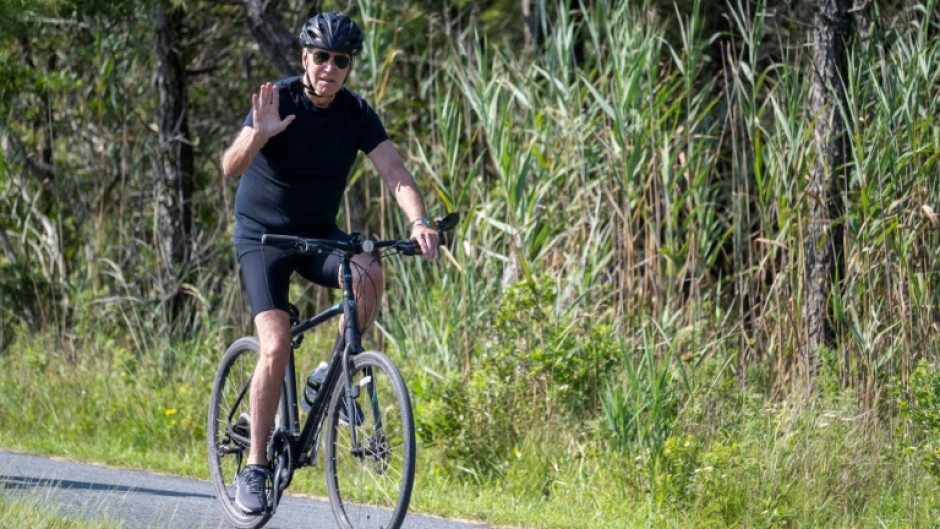 President Joe Biden, vacationing in Rehoboth Beach, Delaware, remained silent as he rode his bike past reporters who asked questions about his rival Donald Trump's legal woes