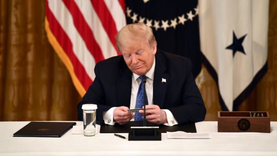 Former US president Donald Trump, holding a debit card during a 2020 cabinet meeting, has broad dicretion to spend campaign funds on legal bills
