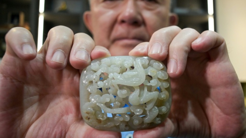 Chang Juben, chairman of Taiwan's Association of Jade Collectors, shows a Yuan dynasty jade belt ornament featuring a carving of a dragon among clouds