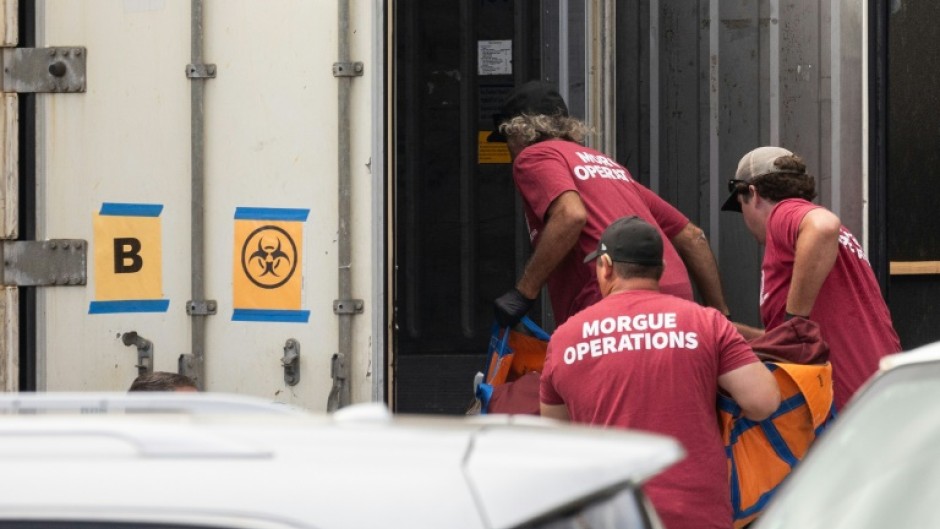 Morgue workers move a body bag into a refrigerated storage container adjacent to the Maui police department's forensic facility, where human remains are stored in the aftermath of the Maui wildfires