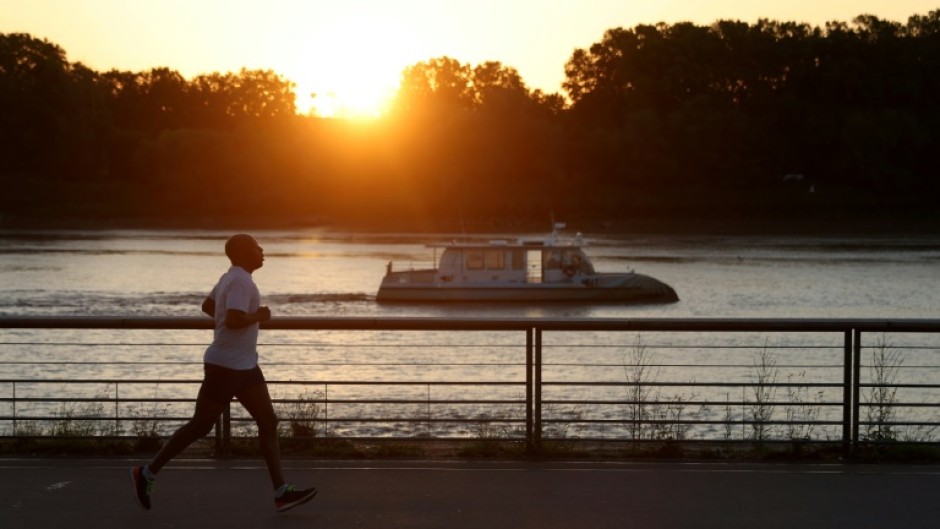 A man jogs along the docks at sunrise to avoid the heat, in Bordeaux, southwestern France