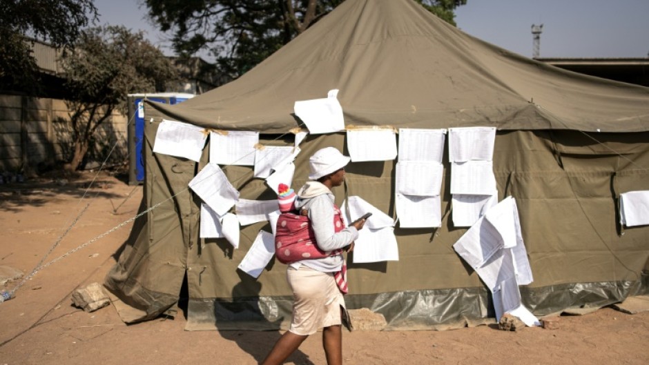 A woman walks past the electoral roll at a polling station in Harare in Zimbabwe's problem-marred vote