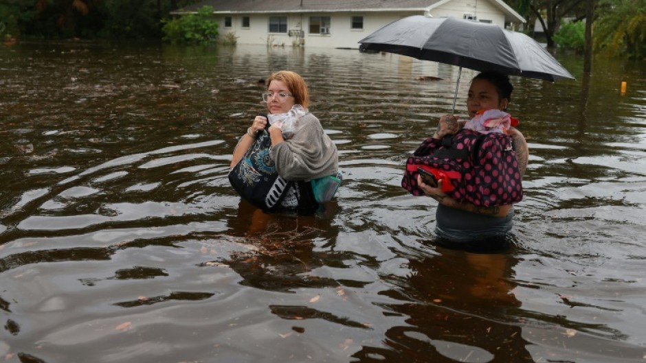 Residents wade through flood waters after having to leave their home on August 30, 2023 in Tarpon Springs, Florida