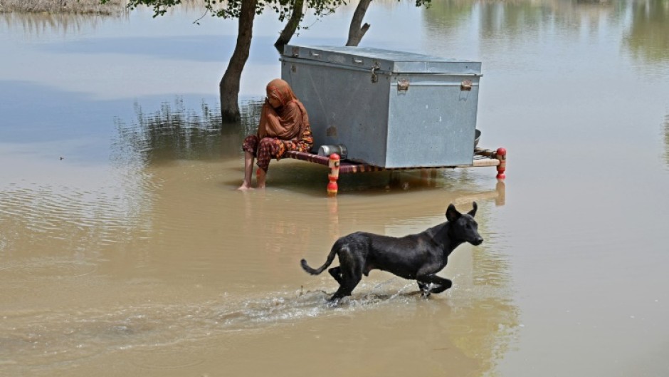 A woman sits with her belongings floodwaters in a village in Pakistan's eastern Punjab province