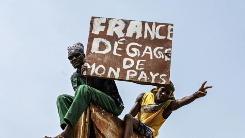 A man burns holds a placard reading 'France get out of my country' 