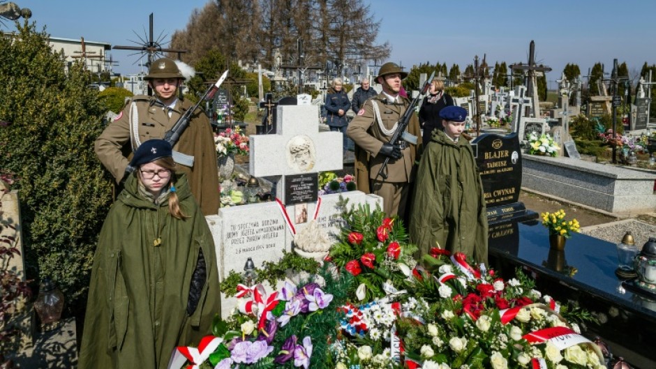 Soldiers stand guard as people lay wreaths  during a ceremony at the grave of The Ulma family