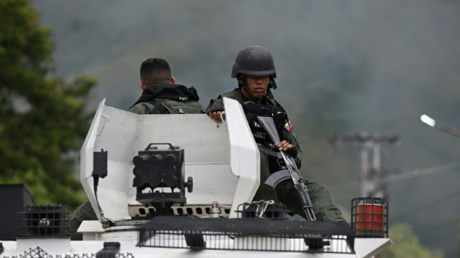Members of the Bolivarian National Guard of Venezuela sit on an armored vehicle in front of the Tocoron prison, where authorities say they seized control from the hands of a powerful gang