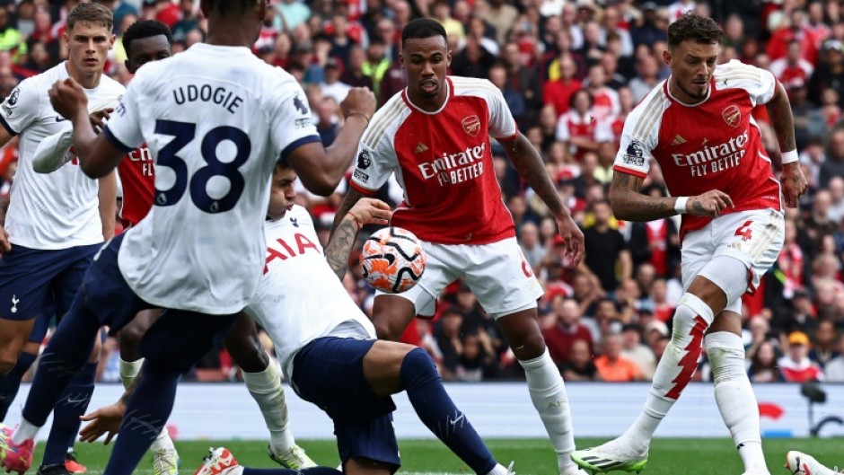 Tottenham's Cristian Romero (C) blocks Ben White's shot with his hand