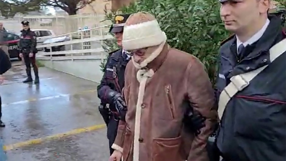 This handout video grab taken and released by the Italian Carabinieri Press Office on January 16, 2023 shows the transfer of mafia boss Matteo Messina Denaro (C) to an undisclosed location following his arrest