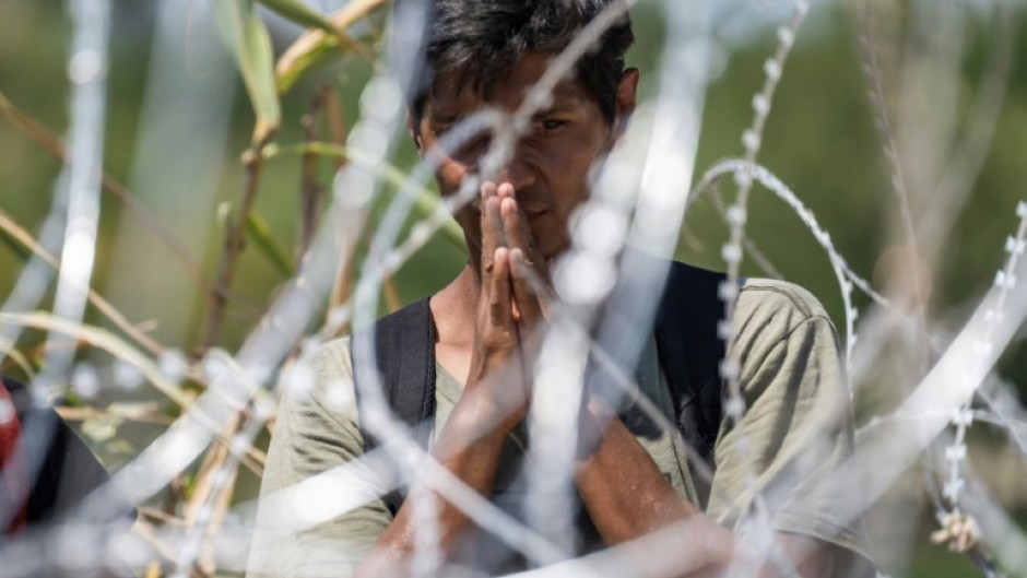 A migrant from Venezuela prays after crossing the Rio Grande to Eagle Pass, Texas