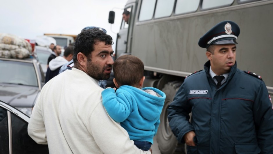 A refugee carrying a child, after crossing the border at a registration centre near the border town of Kornidzor