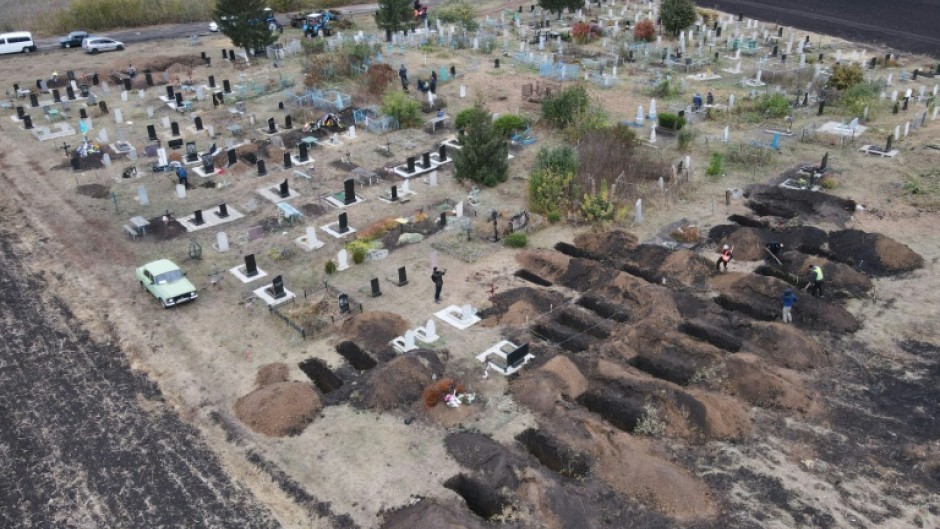 An aerial photograph taken with a drone shows workers digging graves for the victims of an air strike in the Groza village of Ukraine's Kharkiv region