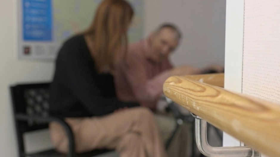Nursing home manager Caroline Wahlberg (L) chats with an elderly man at the fake bus stop
