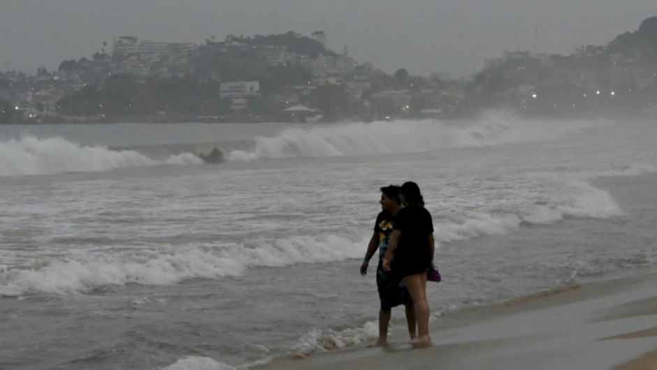 Beach-goers look out to sea as Hurricane Otis approaches the Mexican tourist resort of Acapulco
