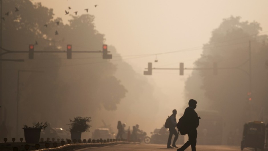 Commuters cross a street amid smoggy conditions in New Delhi in November 2021