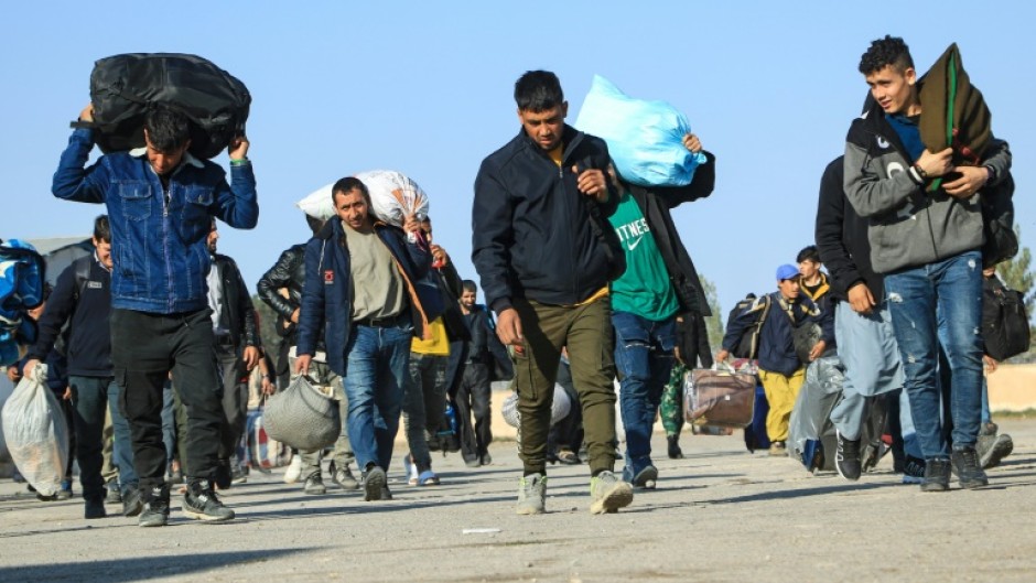 Afghans deported from Iran carry their belongings to a registration centre near the Islam Qala border crossing in Herat province