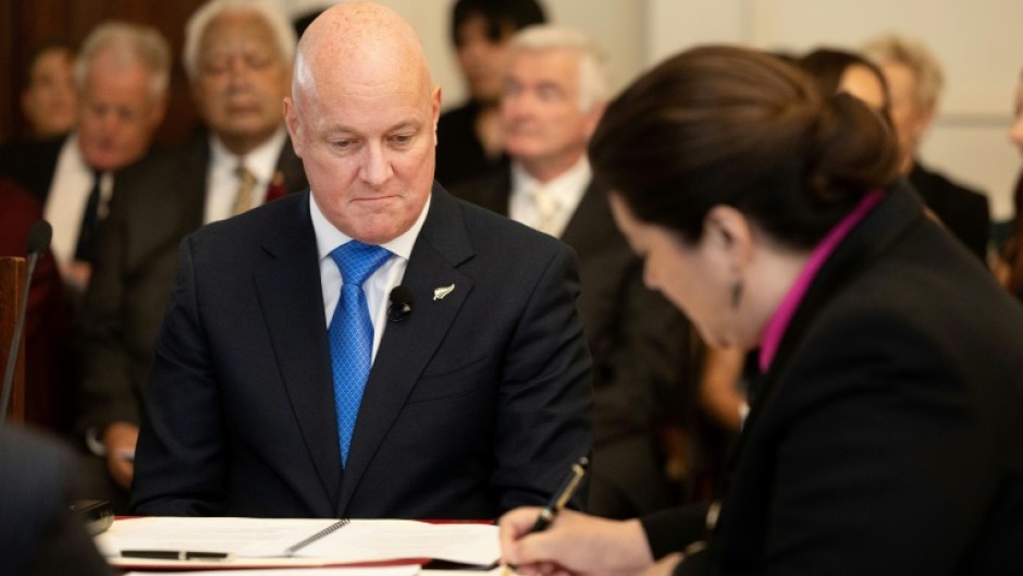 Christopher Luxon (L) looks on as Governor General Dame Cindy Kiro signs documents which formally made him Prime Minister of New Zealand on Monday 
