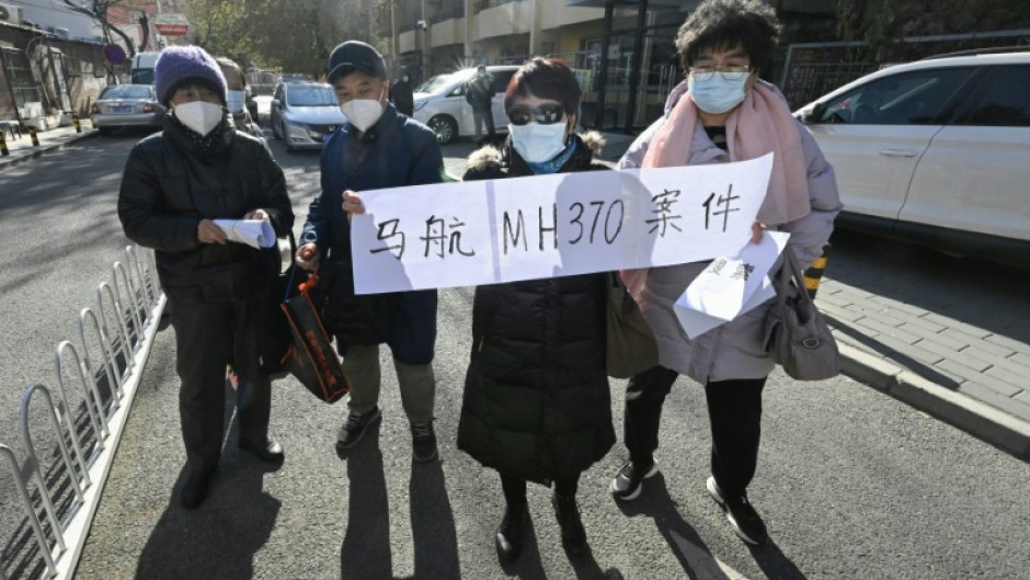 Relatives of passengers of the missing Malaysia Airlines flight MH370 hold a sign reading "Malaysia Airlines MH370 cases" close to a court building in Beijing