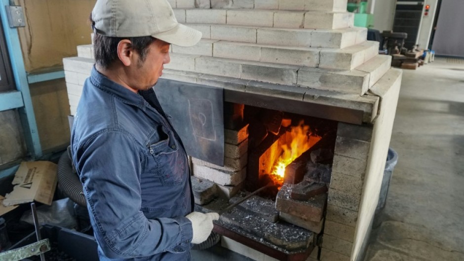 Yoshihiro Yauji, seen placing a piece of metal into a forge, believes 'blades are the foundational root of Japanese culture'