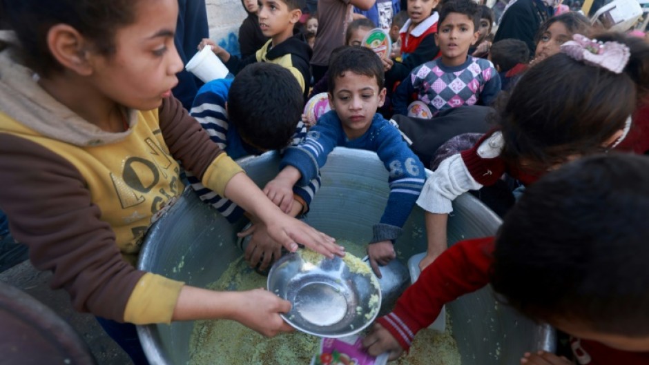 Palestinian children collect food at a donation point provided by a charity group in the southern Gaza city of Rafah