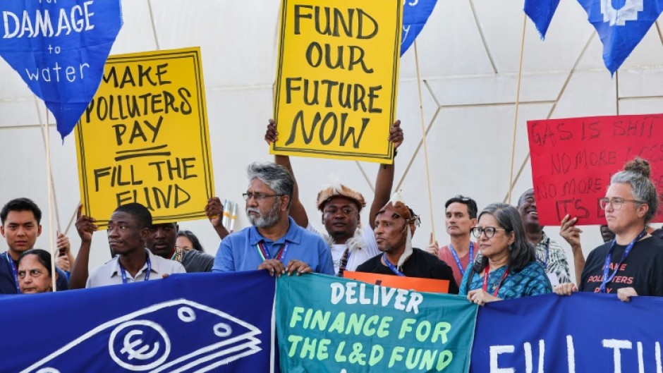 Environmental activists display placards during a demonstration at the venue of the COP28 United Nations climate summit in Dubai 