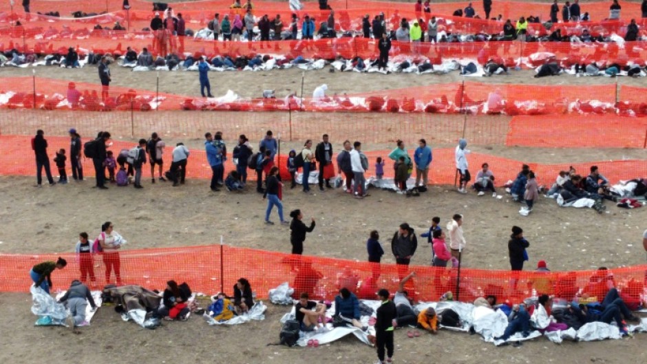 Migrants await processing by immigration authorities after crossing the US-Mexico border in Eagle Pass, Texas, December 20, 2023