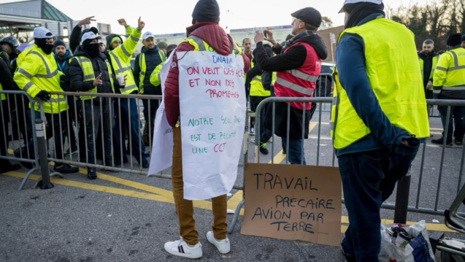 Striker wears a placard reading 'We want actions and not promises, our only mistake is to expect a CCT' during a picket line outside Geneva International Airport