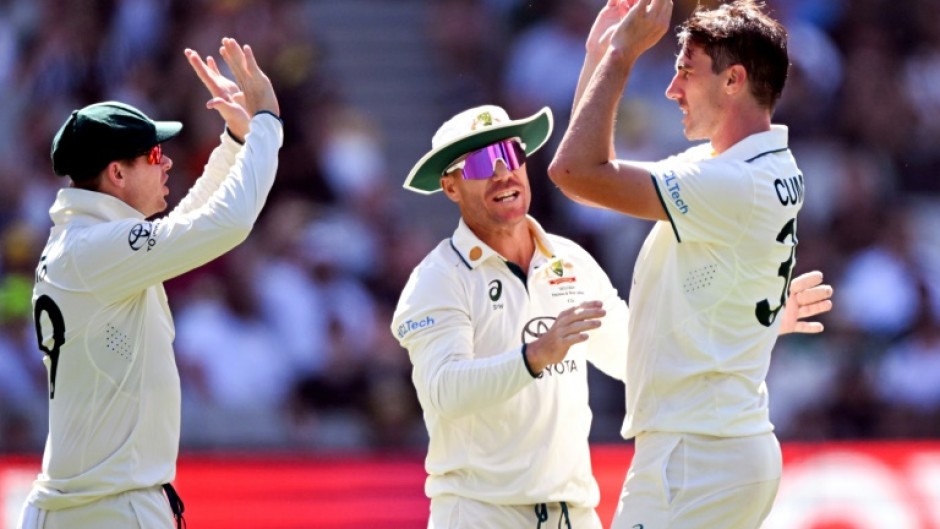 Australia's Pat Cummins (R) celebrates with teammates Steve Smith (L) and David Warner (C) after dismissing Pakistan's batsman Barbar Azam