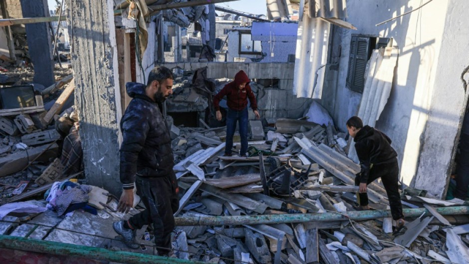 Palestinians search through the rubble of a building following an Israeli strike in the southern Gaza Strip on Tuesday