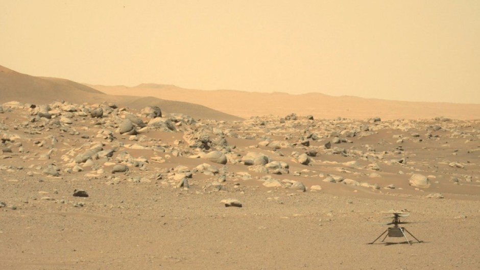 NASA's tiny Ingenuity helicopter is seen sitting on the surface of Mars in a photograph taken by the rover Perseverance 