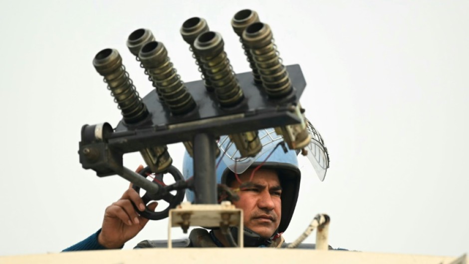 An Indian security officer stands atop an armoured vehicle at a roadblock during protests called by farmers on Tuesday