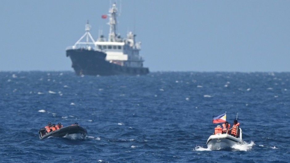 Chinese coast guard personnel aboard a rigid hull inflatable boat (front L) trail a Philippine vessel (front R) near the China-controlled Scarborough Shoal