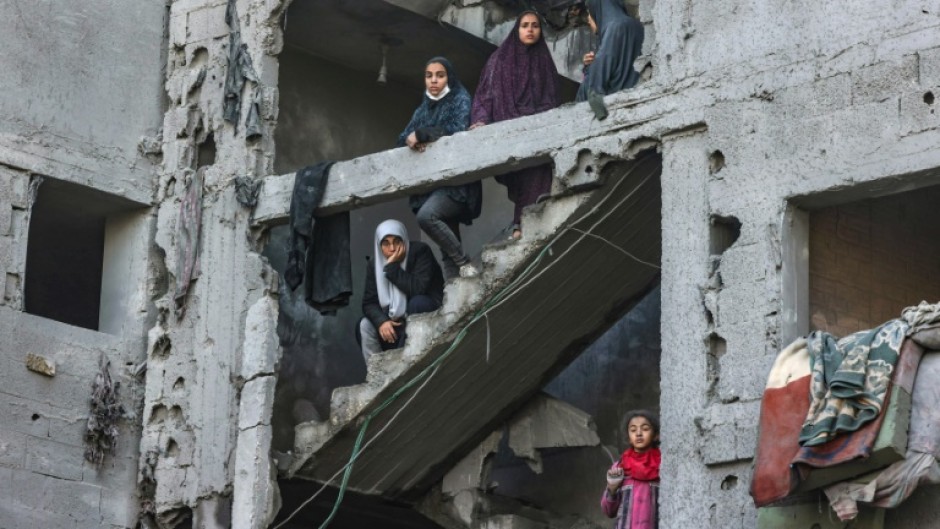 Palestinian women and children look at the damage from overnight Israeli air strikes in the Rafah refugee camp in the southern Gaza Strip