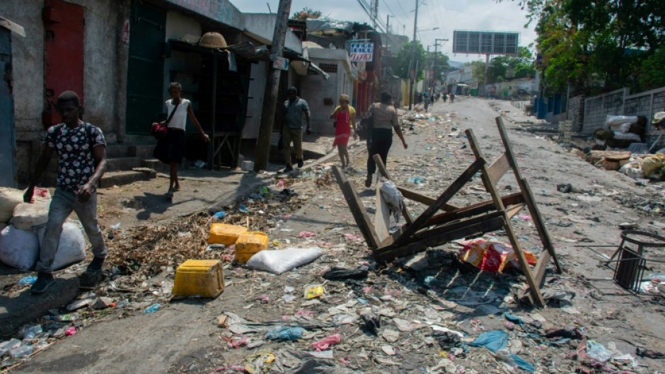 Haitians walk past a barricade March 20, 2024
