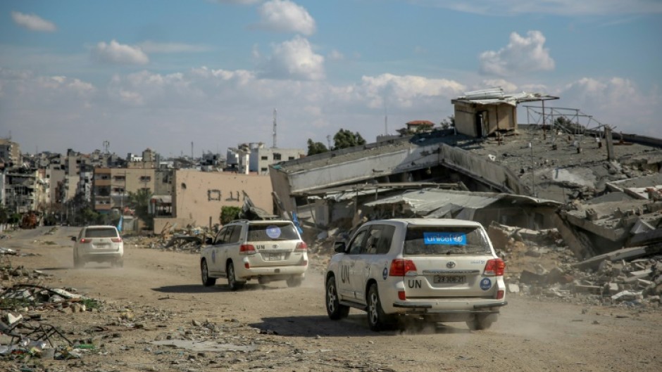 UN vehicles drive past buildings destroyed by previous Israeli strikes Gaza City