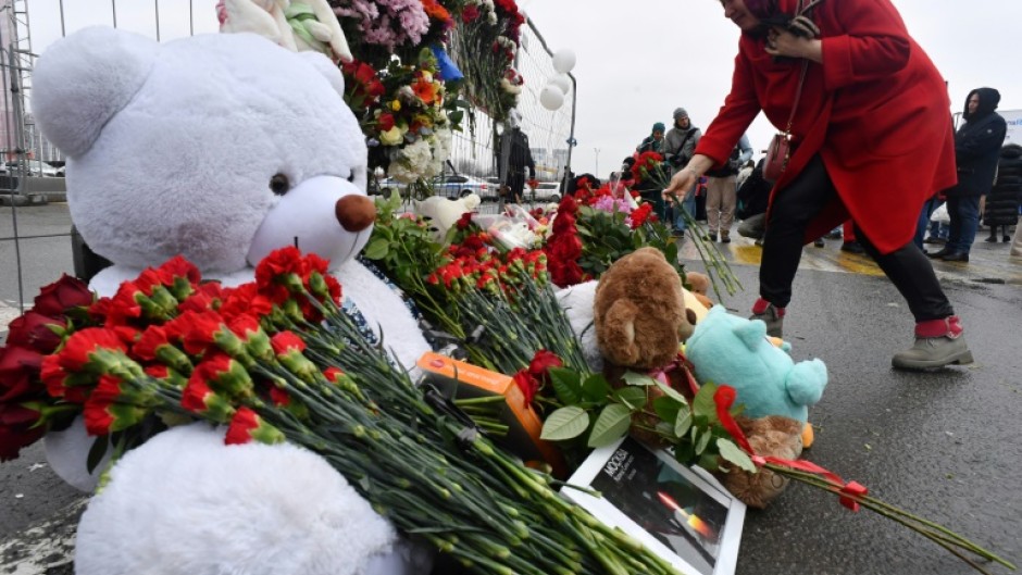 A woman lays flowers at a makeshift memorial to the victims in front of the Crocus City Hall outside Moscow