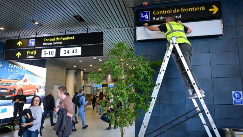 A Romanian worker changes the signs for passengers at Henri Coanda International Airport ahead of Romania and Bulgaria taking a first step into the Schengen visa free travel area on Sunday