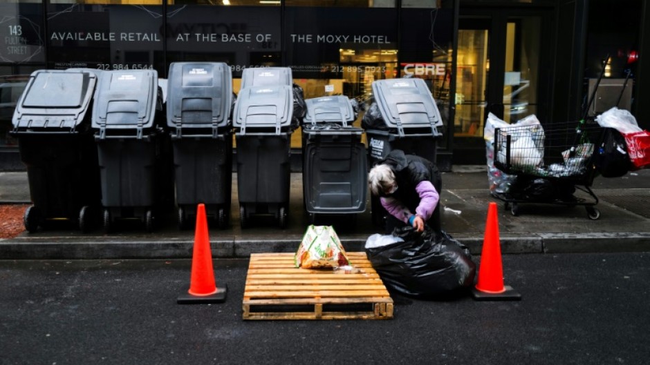 A woman searches through a trash bag in Manhattan on March 20, 2024