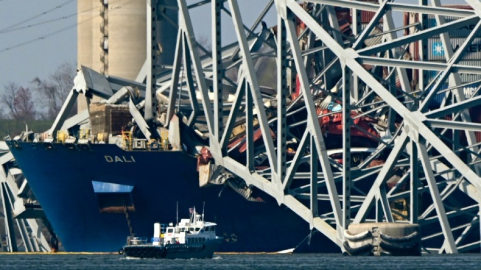 The collapsed Francis Scott Key Bridge lies on top of the container ship Dali in Baltimore, Maryland, on March 29, 2024, as clean-up work begins