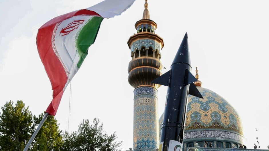 Iranians in central Tehran lift up a flag and the mock-up of a missile during a celebration following Iran's unprecedented attack by missiles and drones on Israel